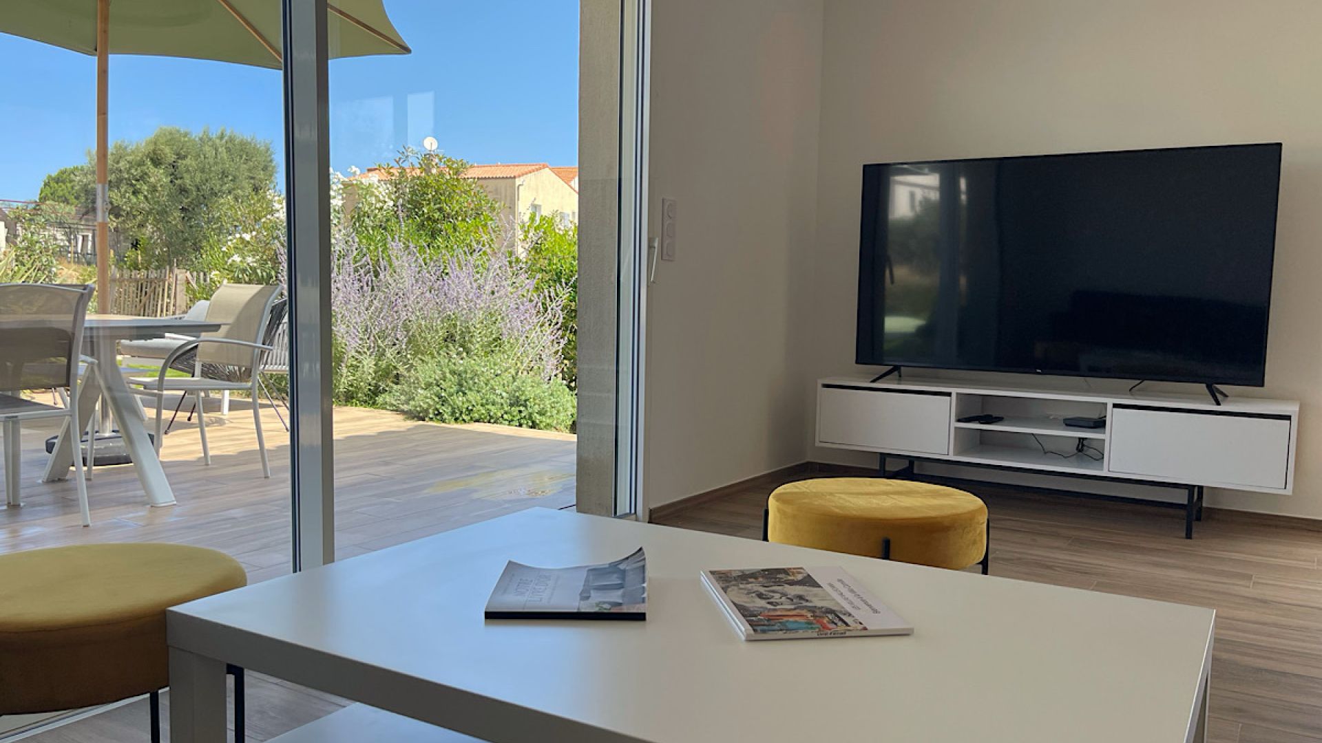 Salon moderne équipé d'un canapé de chez Cuir center 6 assises, d'un télévision murale connectée. Le salon offre une vue complète sur la terrasse piscine et la baie de Calvi