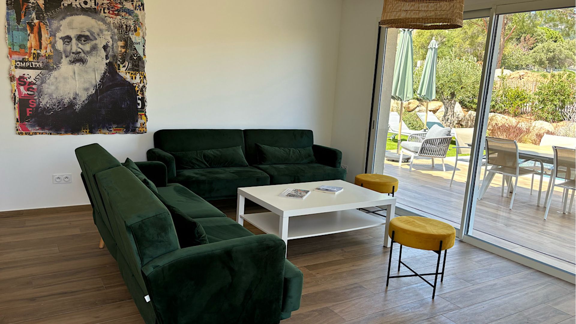 Salon moderne équipé d'un canapé de chez Cuir center 6 assises, d'un télévision murale connectée. Le salon offre une vue complète sur la terrasse piscine et la baie de Calvi